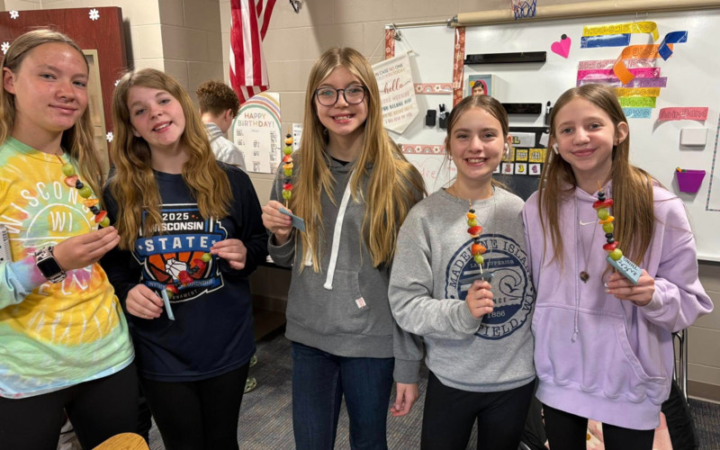 group of girls holding fruit on skewers